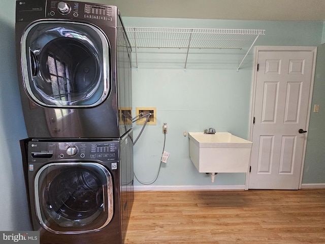 laundry area with sink, washer hookup, stacked washer / drying machine, and light hardwood / wood-style flooring