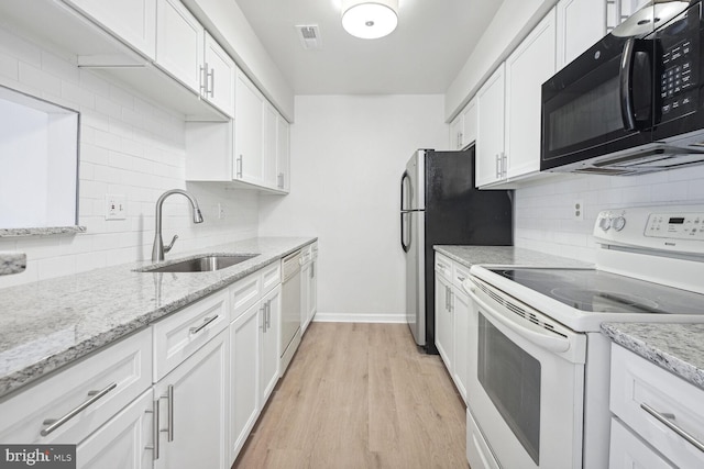 kitchen featuring sink, white appliances, light stone countertops, light hardwood / wood-style floors, and white cabinets