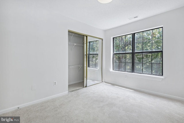 unfurnished bedroom with carpet, a textured ceiling, and a closet