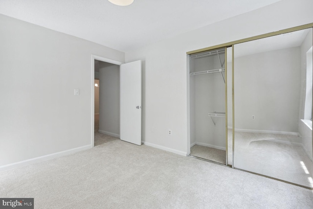 unfurnished bedroom featuring light carpet and a closet