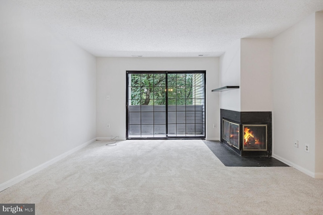 unfurnished living room with dark colored carpet, a multi sided fireplace, and a textured ceiling