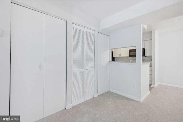 unfurnished bedroom featuring light carpet and two closets