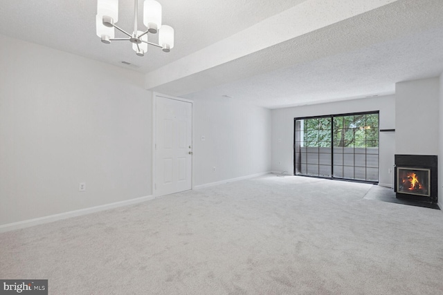 unfurnished living room featuring carpet, an inviting chandelier, and a textured ceiling