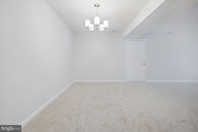 carpeted spare room with a textured ceiling and a chandelier