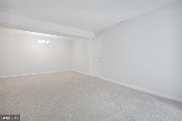 unfurnished room with a textured ceiling, carpet, and a notable chandelier