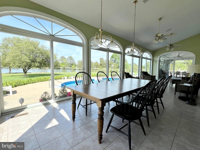 tiled dining area with a water view, ceiling fan with notable chandelier, and vaulted ceiling