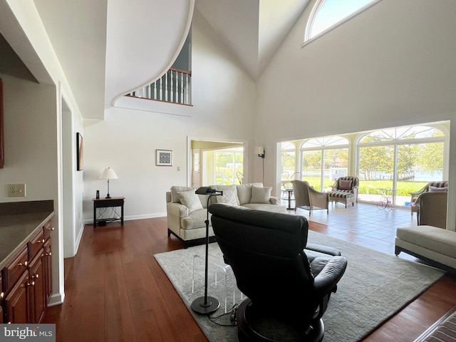 living room with dark wood-type flooring and a high ceiling