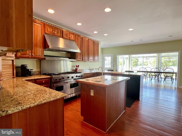 kitchen featuring a center island with sink, plenty of natural light, dark wood-type flooring, and double oven range