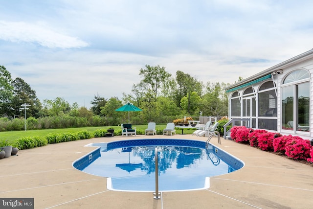 view of swimming pool with a sunroom, a patio area, and a lawn