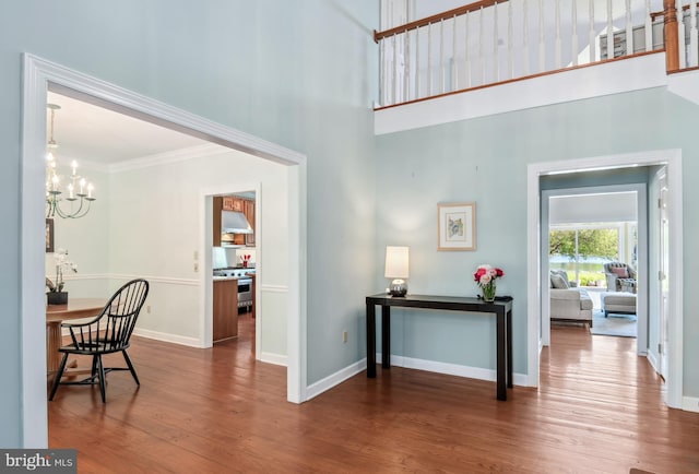 foyer entrance featuring ornamental molding, a high ceiling, a notable chandelier, and hardwood / wood-style flooring