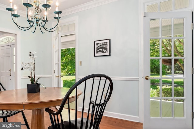 dining space featuring hardwood / wood-style floors, a notable chandelier, and crown molding