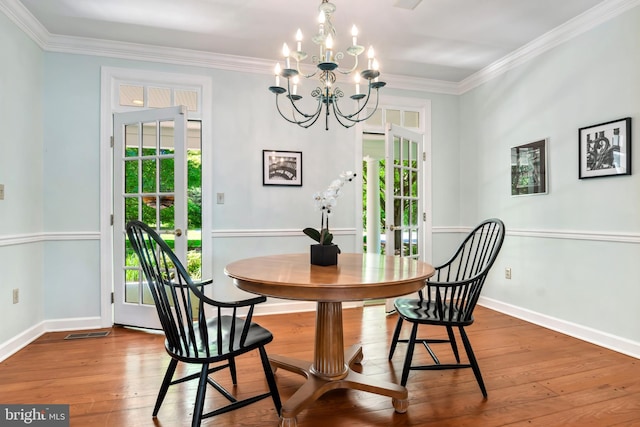 dining space featuring a notable chandelier, wood-type flooring, and crown molding