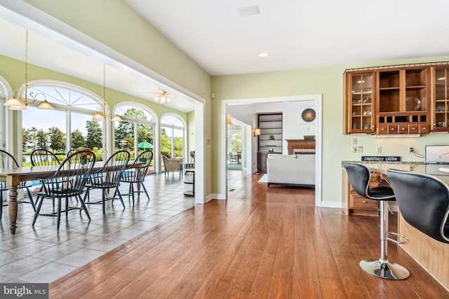 dining area featuring wood-type flooring and ceiling fan with notable chandelier