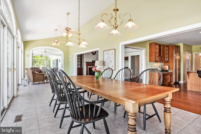 dining room with light hardwood / wood-style floors, high vaulted ceiling, and ceiling fan with notable chandelier