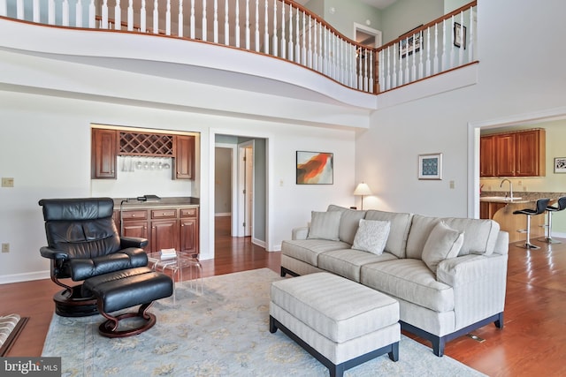 living room with dark wood-type flooring, a towering ceiling, and sink