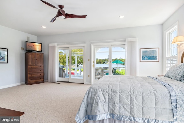 bedroom featuring access to outside, multiple windows, light colored carpet, and ceiling fan