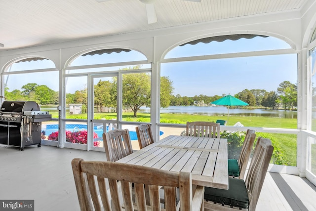 sunroom featuring a water view and ceiling fan