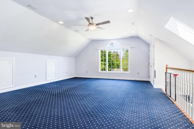 additional living space with lofted ceiling with skylight, ceiling fan, and dark colored carpet