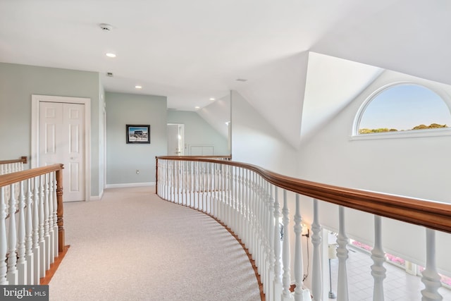 corridor with vaulted ceiling and light carpet