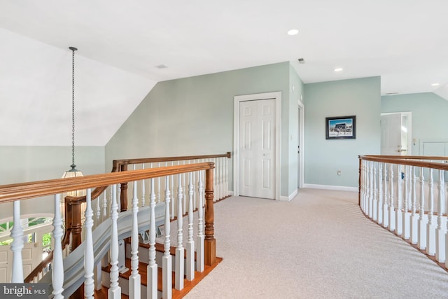 hallway featuring lofted ceiling and light colored carpet