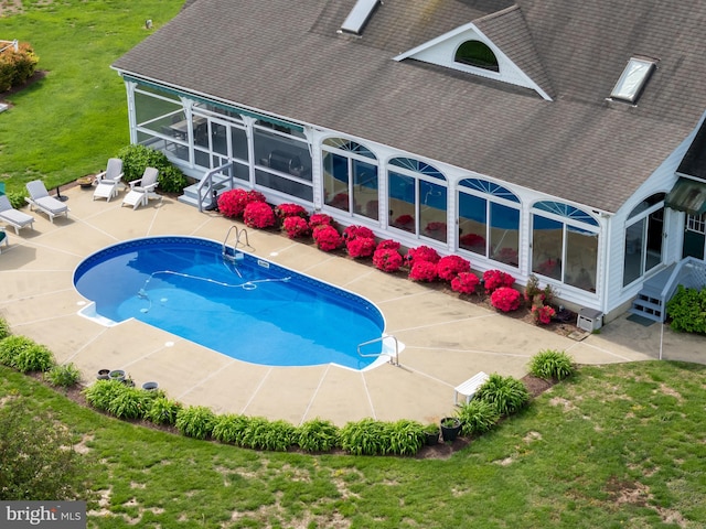 view of swimming pool featuring a patio area, a lawn, and a sunroom