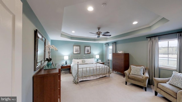 bedroom featuring light colored carpet, ceiling fan, crown molding, and a tray ceiling