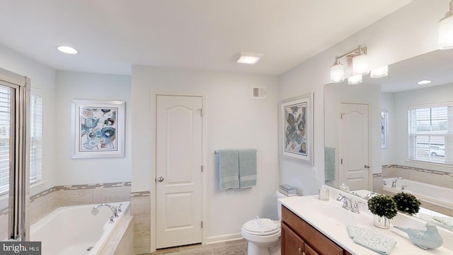 bathroom featuring toilet, tiled tub, and vanity