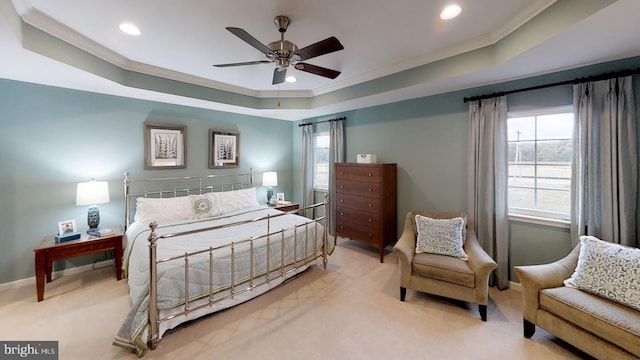 carpeted bedroom with ornamental molding, ceiling fan, a tray ceiling, and multiple windows