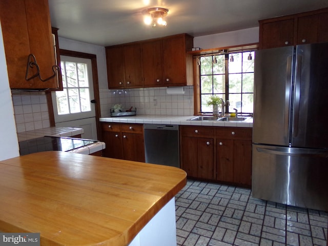 kitchen featuring dishwasher, backsplash, stainless steel refrigerator, and sink