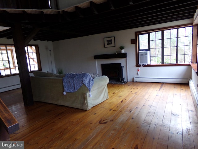 unfurnished living room with hardwood / wood-style floors and a baseboard heating unit