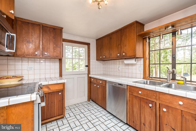 kitchen with backsplash, sink, stainless steel appliances, and tile countertops