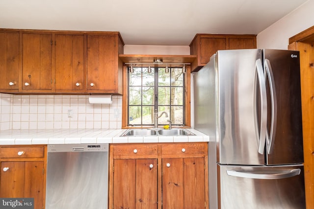 kitchen featuring tile counters, decorative backsplash, sink, and appliances with stainless steel finishes