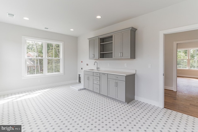 interior space with gray cabinetry, light carpet, and sink