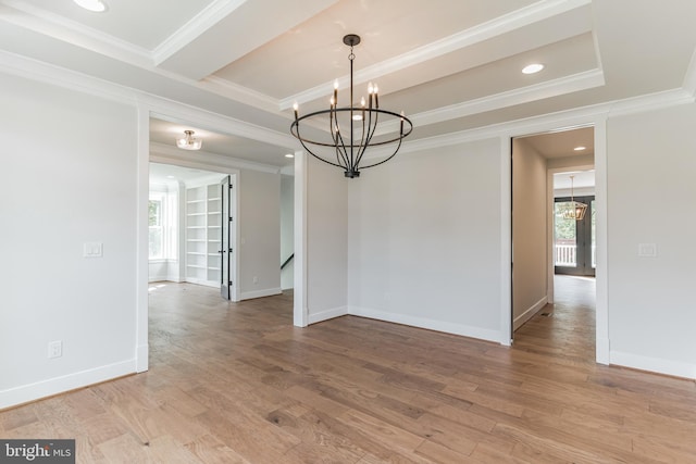 unfurnished room featuring ornamental molding, wood-type flooring, a notable chandelier, and a tray ceiling