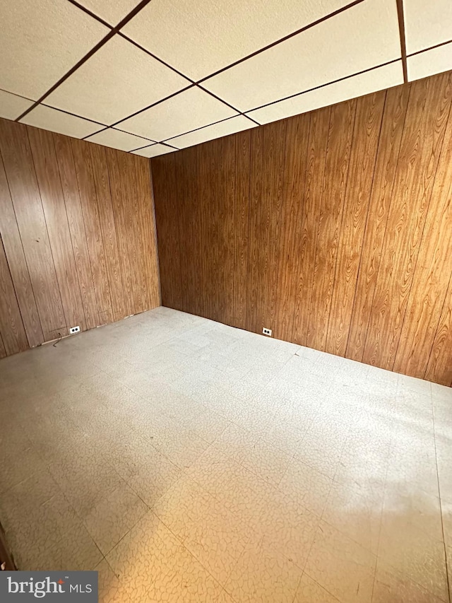 empty room featuring wooden walls and a paneled ceiling