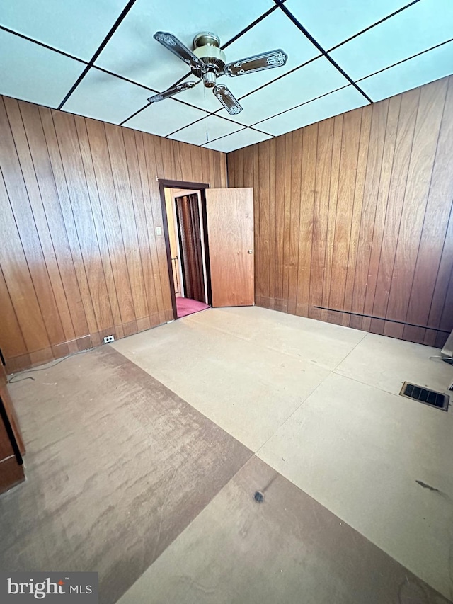 unfurnished room with ceiling fan and wooden walls