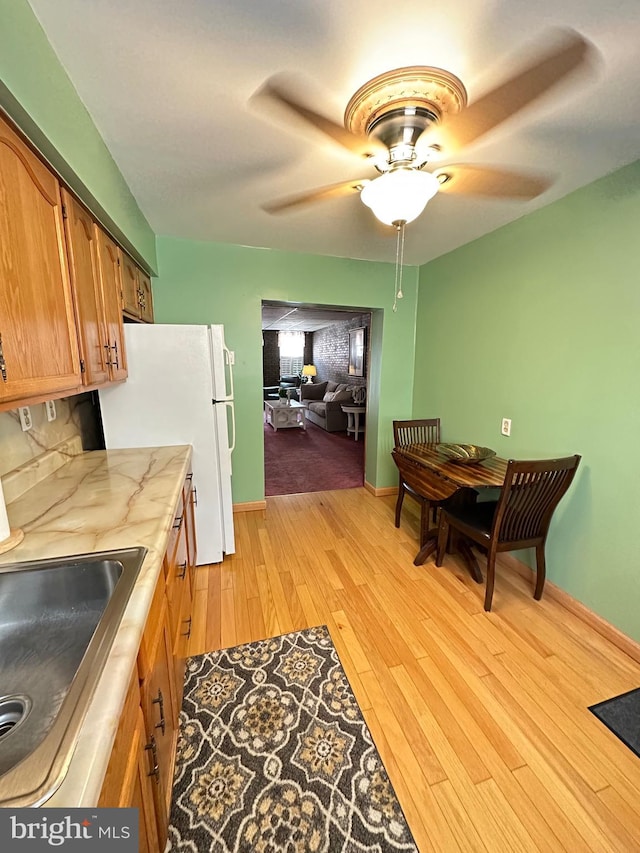 kitchen featuring ceiling fan, light hardwood / wood-style flooring, sink, and white fridge