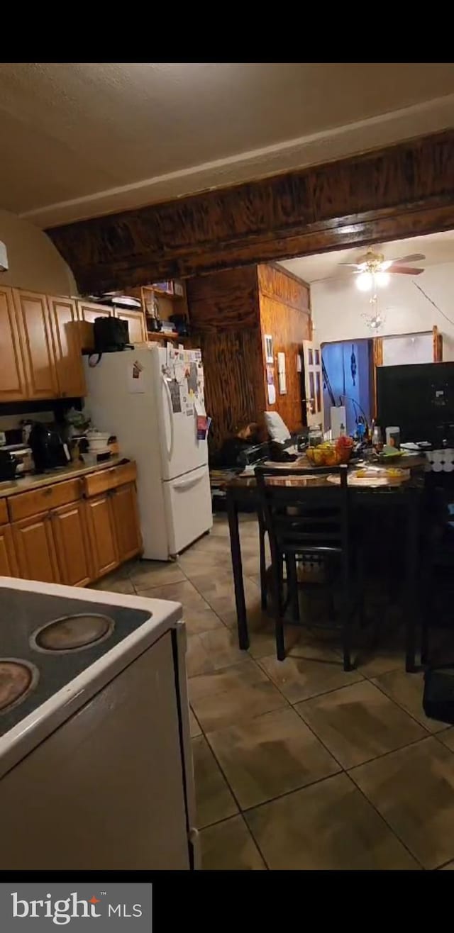 kitchen featuring stove, white fridge, ceiling fan, and light tile floors