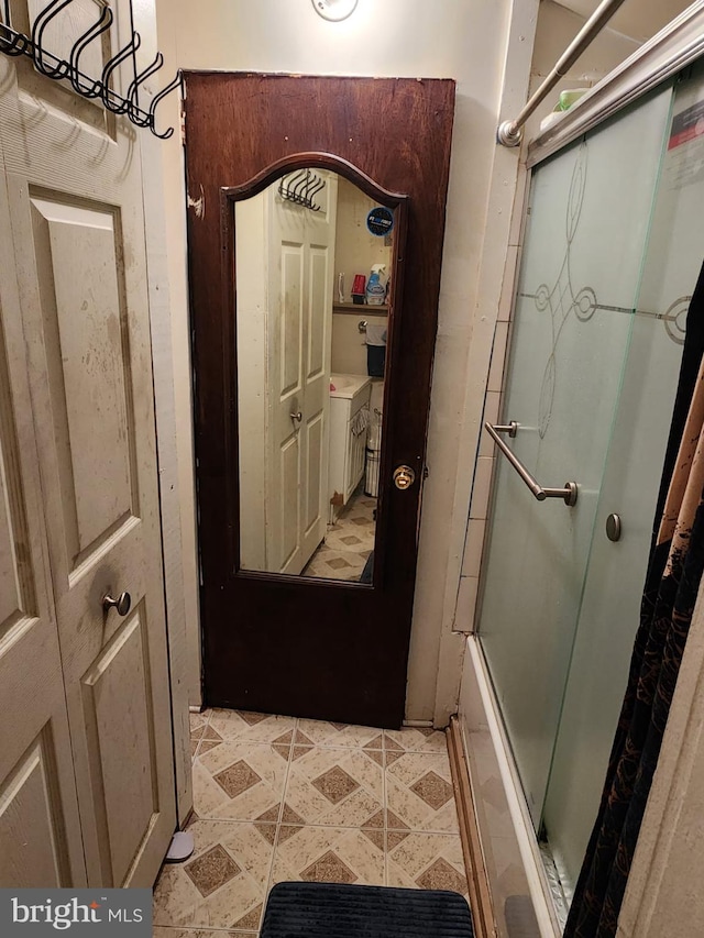 interior space with shower / bath combination with glass door and tile floors