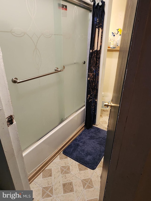 bathroom featuring tile floors and shower / bath combination with glass door