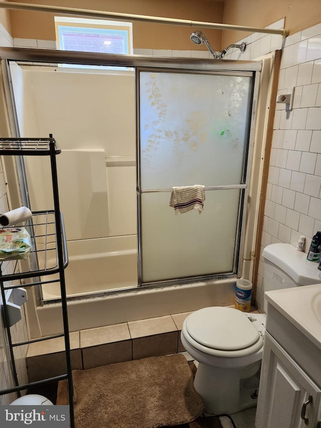 full bathroom featuring vanity, tile walls, toilet, and shower / bath combination with glass door