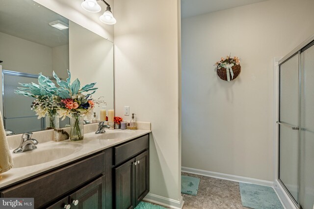 bathroom with tile flooring, dual sinks, large vanity, and a shower with shower door