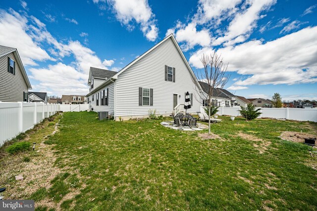 rear view of property featuring a patio, a lawn, and central AC