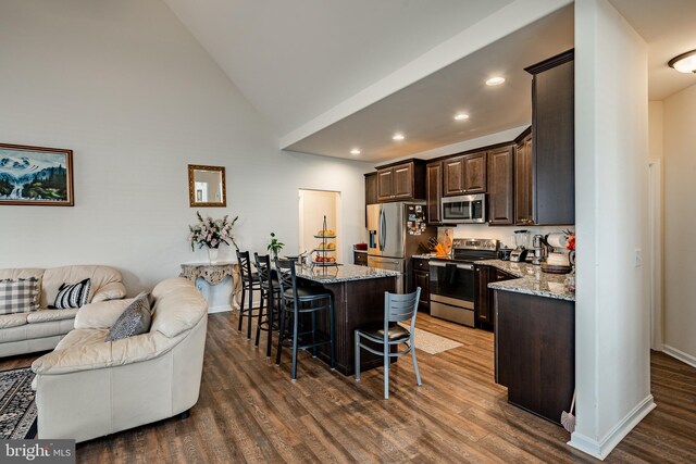 kitchen featuring dark hardwood / wood-style floors, a kitchen breakfast bar, stainless steel appliances, and light stone countertops