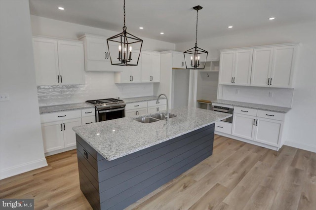 kitchen featuring pendant lighting, sink, stainless steel range with gas cooktop, white cabinetry, and light hardwood / wood-style flooring