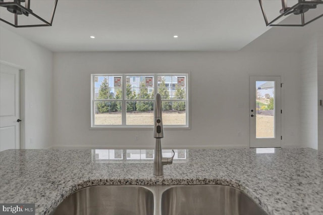 kitchen with sink, a notable chandelier, and light stone counters