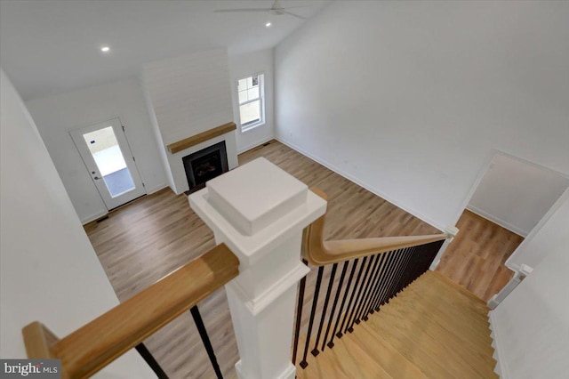 stairway with lofted ceiling, ceiling fan, and light wood-type flooring