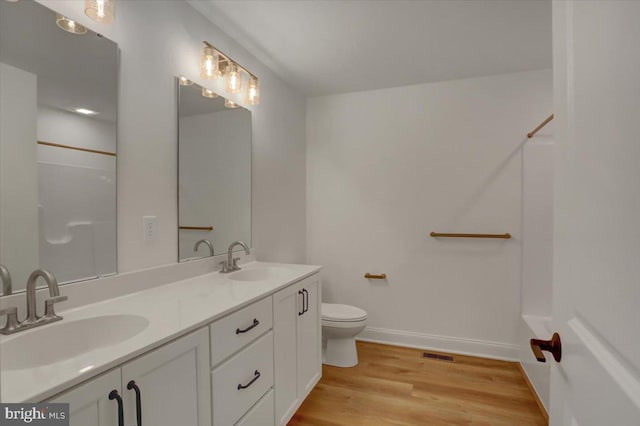 bathroom with double sink, toilet, hardwood / wood-style flooring, and oversized vanity