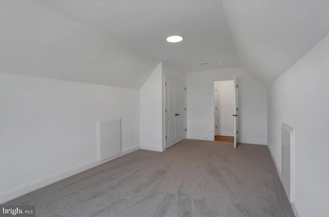 additional living space with light colored carpet and vaulted ceiling