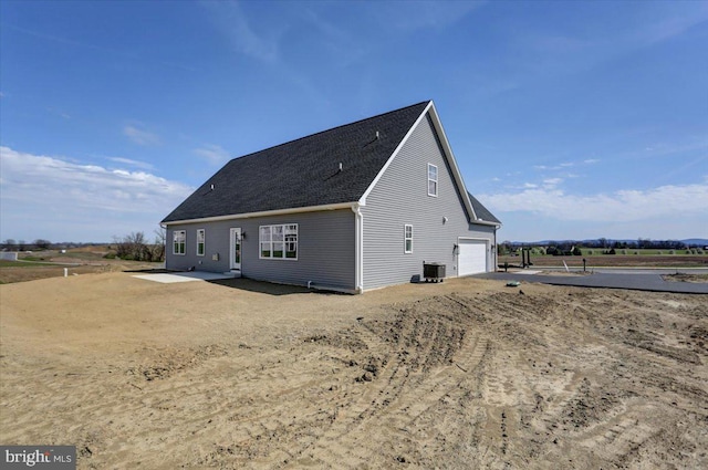 back of property featuring central AC unit and a garage